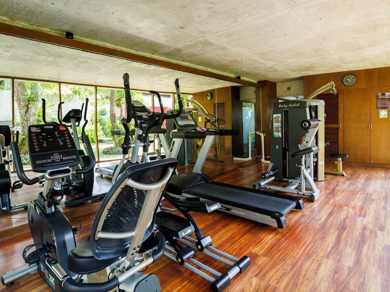 Moderní fitness vybavení v světlé posilovně s dřevěnou podlahou a velkým oknem.