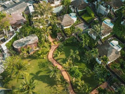 Widok z lotu ptaka na ogród z wijącą się ścieżką i kilkoma okalającymi budynkami.