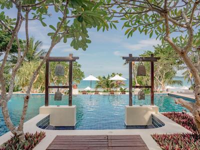 Ein luxuriöser Pool mit Liegestühlen und Sonnenschirmen, umgeben von tropischer Vegetation.