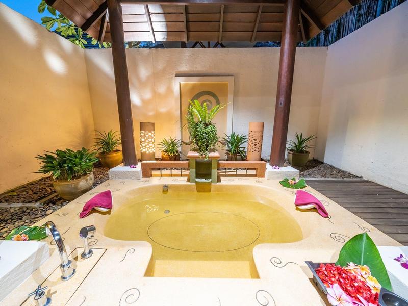 Przytulna wanna na zewnątrz z roślinami i dekoracjami w relaksującej atmosferze.