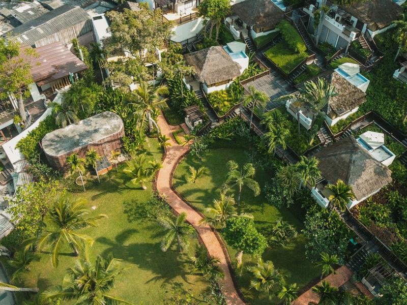 Widok z lotu ptaka na ogród z wijącą się ścieżką i kilkoma okalającymi budynkami.