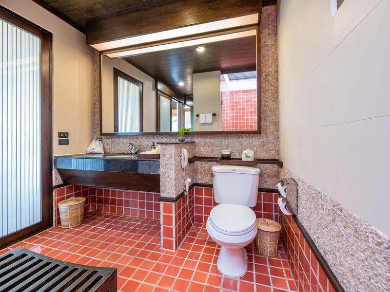 Nowoczesna łazienka z czerwonymi płytkami, umywalką, toaletą i dużymi lustrami.