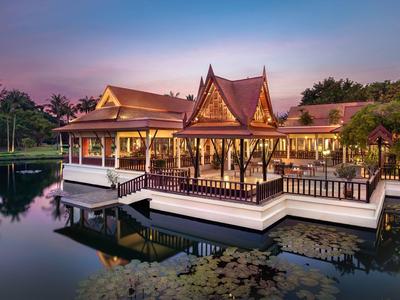 Traditional Thai wooden pavilion on water at sunset in a resort