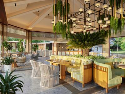 Bright hotel dining area with green chairs and plants, cozy atmosphere with large chandelier.