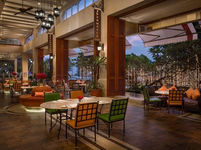 Modern hotel lounge with colorful chairs and tables in spacious area with glass walls.