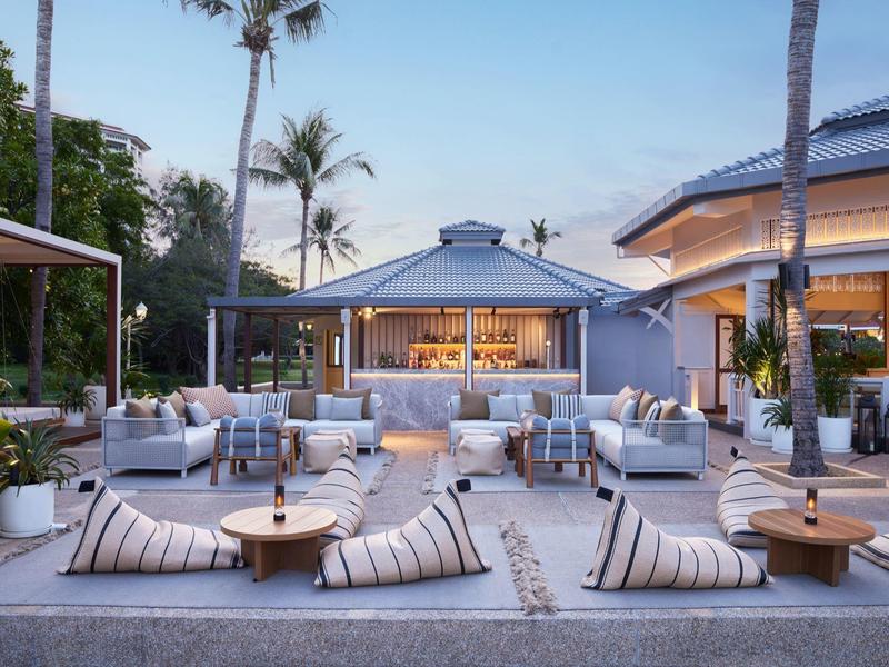 Luxury hotel outdoor area with seating, low tables, and palm trees.
