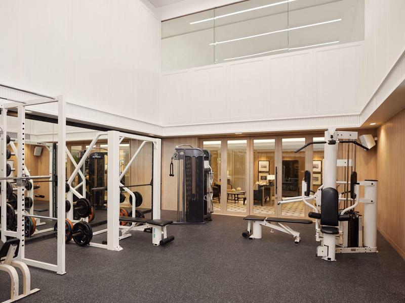 Bright gym with modern equipment and wooden wall paneling in a hotel.