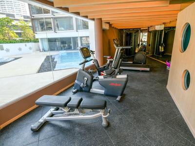 Moderner Fitnessraum mit Blick auf den Pool und verschiedenen Kraftgeräten.