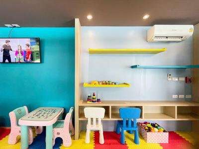 Stanza giochi colorata per bambini con tavolo, piccole sedie e scaffali con giocattoli.