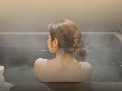 Donna che si rilassa in un bagno termale fumante.