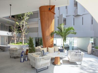 Area esterna moderna con poltrone comode, tavoli rotondi e luce di palma in hotel.