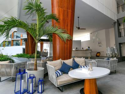 Modernes Hotel-Loungemöbel mit Sofa, runder weißer Tisch und grünen Pflanzen im Innenbereich.