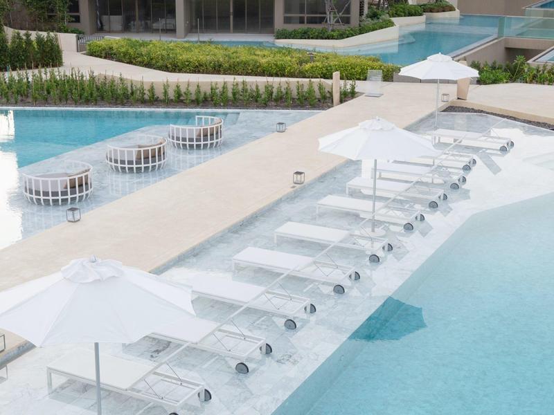 Area piscina moderna con lettini subacquei e ombrelloni bianchi