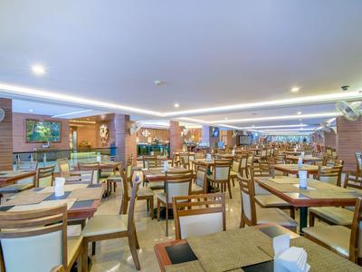 Světla a prostorná restaurace s mnoha dřevěnými stoly a židlemi, moderní osvětlení.