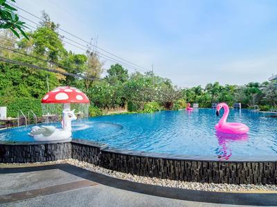 Venkovní bazén s nafukovacími kruhy houby a plameňáka v tropickém prostředí.