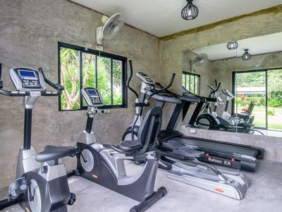 Palestra moderna con cyclette, tapis roulant e grandi finestre con vista sul verde.