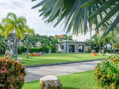 Area giardino verde con palme e un alloggio moderno sullo sfondo.