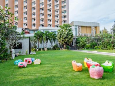 Trávník před hotelem s barevnými pohodlnými sedačkami a palmami.