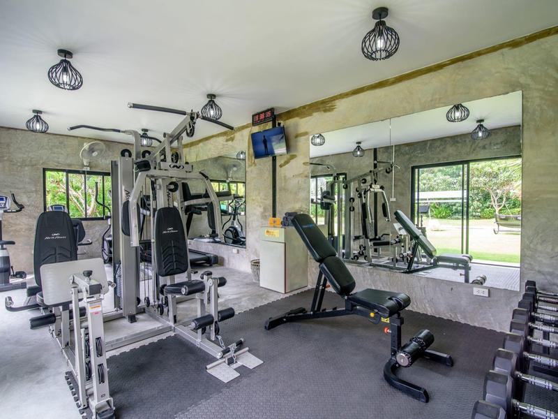 Moderní fitcentrum s různými cvičebními stroji a velkým zrcadlem na stěně.