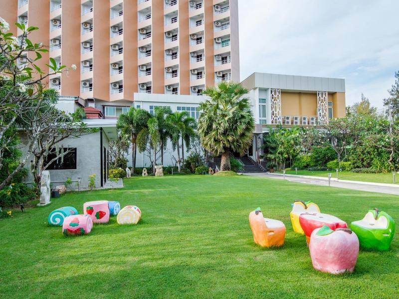 Trávník před hotelem s barevnými pohodlnými sedačkami a palmami.