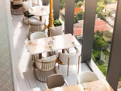 Hell eingerichteter Balkon mit Tischen und Stühlen, Blick auf Garten und Häuser