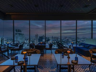 Luxury restaurant with large glass windows overlooking the city at dusk.