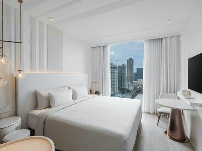 Modernes Hotelzimmer mit großem Fenster und Stadtblick, weißes Bett und minimalistisches Design.