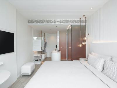 Minimalist modern hotel room with large bed, TV, and illuminated wall panels.