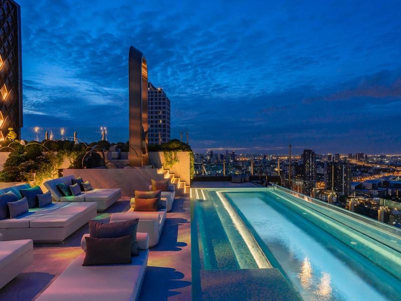 Luxurious rooftop pool with comfortable loungers and city view at dusk.