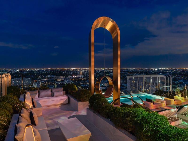 Luxurious rooftop terrace with modern seating and illuminated art piece at night.