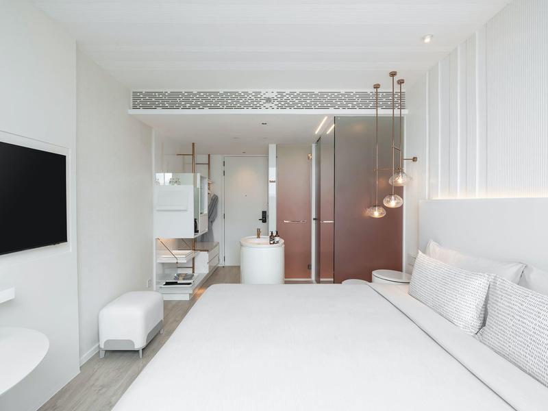 Minimalist modern hotel room with large bed, TV, and illuminated wall panels.