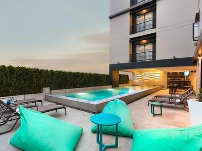 Modern outdoor area with pool, seating, and green privacy screen at dusk.
