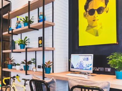 Moderne werkplek met houten planken, planten en een computer voor een geel kunstposter.