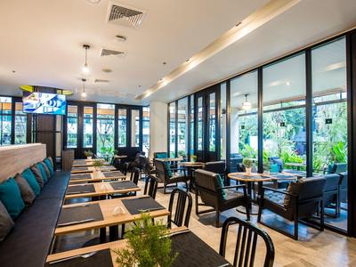 Bright, modern dining area with tables, chairs, and large windows overlooking greenery.