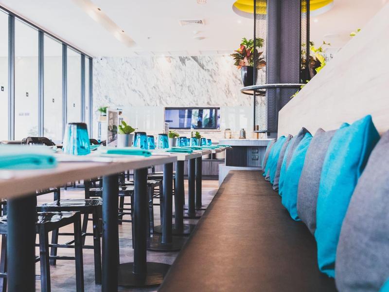 Modern dining area with black bench seating and blue cushions in bright space.