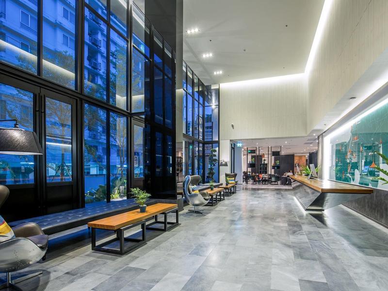 Modern hotel lobby with large windows, seating areas, and bright lighting.