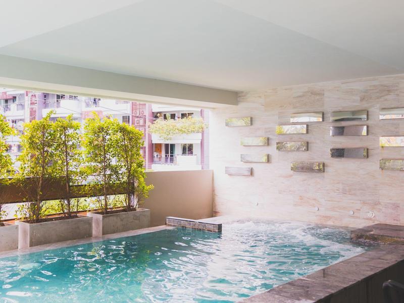 Heated indoor pool with air bubbles and windows overlooking buildings and plants.