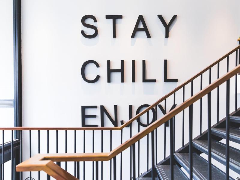 Modern stairway with 'STAY CHILL ENJOY' wall text in a hotel.