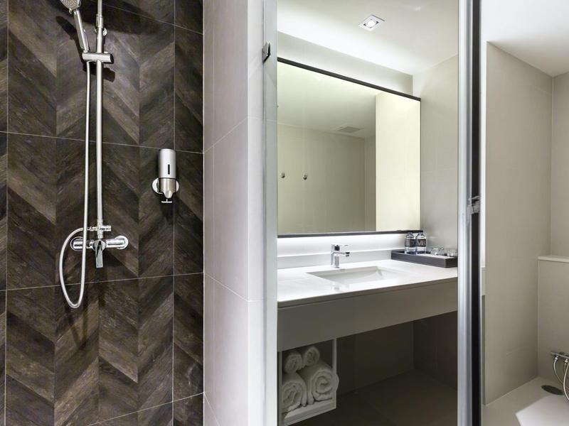 Modern bathroom with walk-in shower and sink under illuminated mirror.