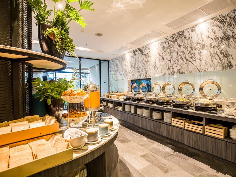 Buffet area in a modern breakfast room with marble wall and fresh plants.
