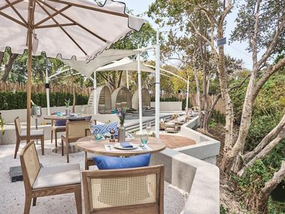 Cozy patio with dining area, umbrella, and view of lush trees.