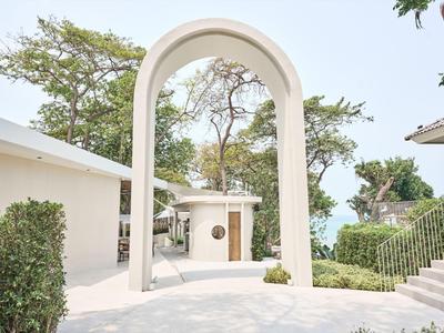 A bright courtyard with a large archway and green bushes on a sunny day.