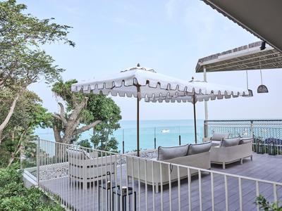Terrace with seating area, sun umbrella, and sea view under clear sky.