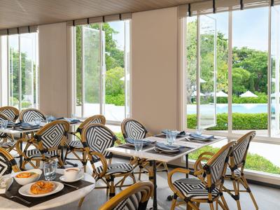 Bright restaurant with bistro chairs and view of terrace and garden.