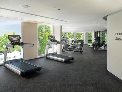 Modern gym with treadmills, bikes, and weights in a hotel.