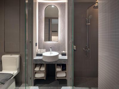 Modern bathroom with toilet area, illuminated sink, and walk-in shower.