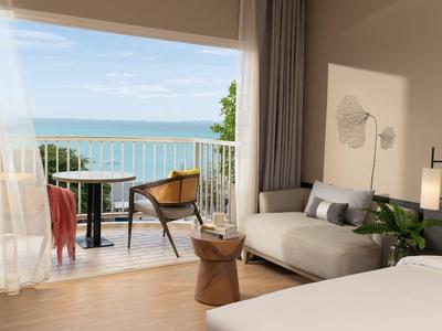 Modern hotel room with sea view and balcony seating area.