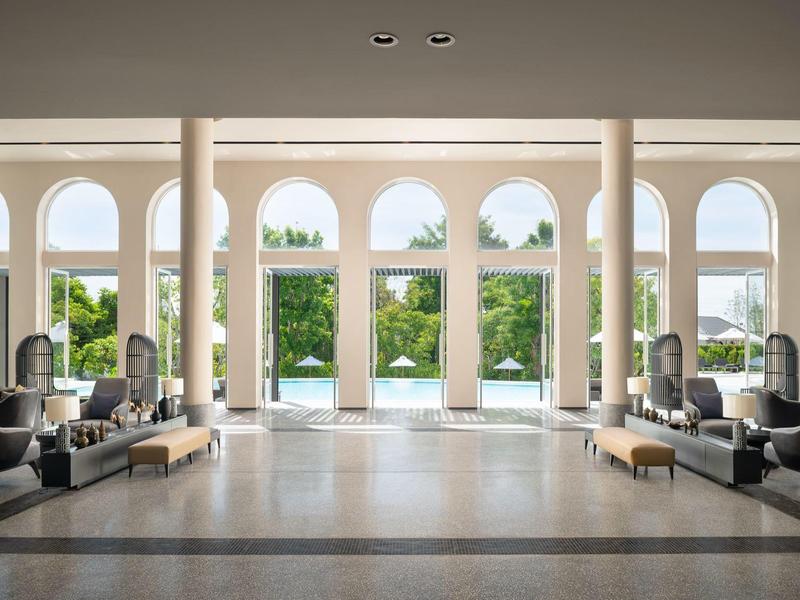 Spacious bright lobby with seating and garden view through tall windows.