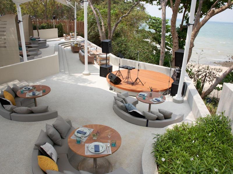 Open seating area with modern round sofas and tables, overlooking the beach and sea.
