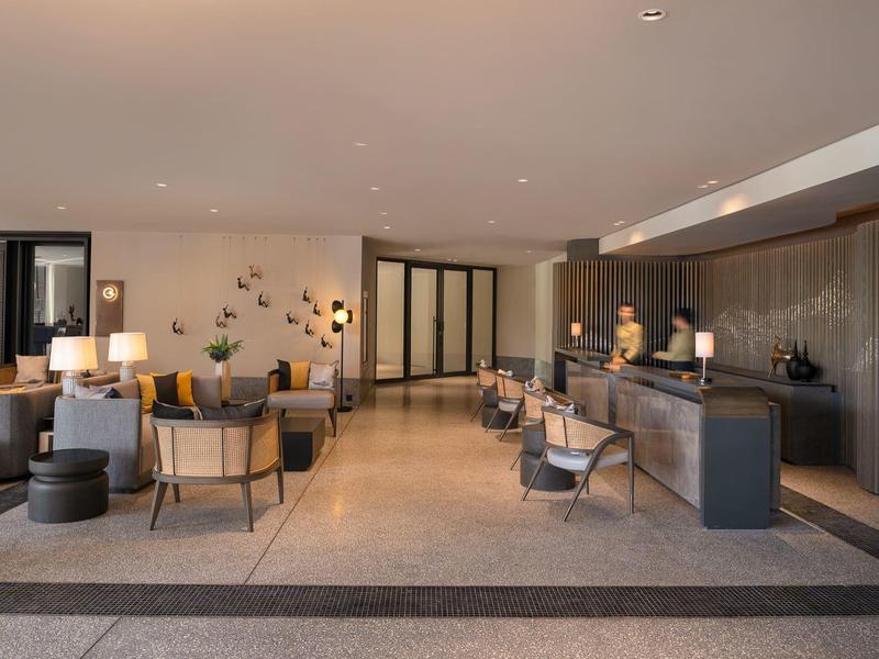 Modern hotel lobby area with reception desk, seating, and warm lighting.